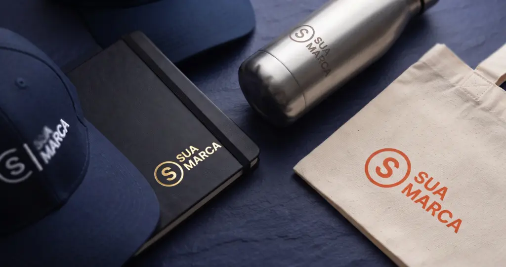 Brindes personalizados com diferentes técnicas de gravação: hot stamping em caderno, bordado em boné, laser em garrafa de inox e silk screen em ecobag